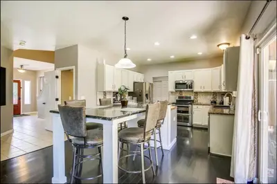 a kitchen with white cabinets and a island with bar stools at Near to DIA Airport retreat And 20 Min To Downtown Denver in Henderson