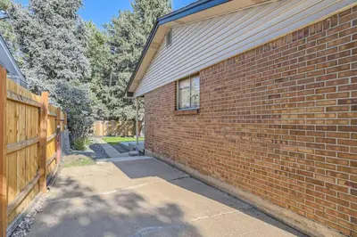 a brick wall next to a house with a fence at Pet Friendly 3 Bedroom Near to Red Rocks And Belmar In Denver in Lakewood