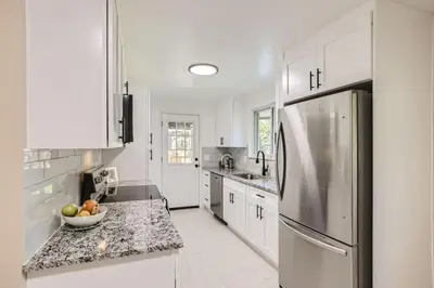 a kitchen with white cabinets and a stainless steel refrigerator at Pet Friendly 3 Bedroom Near to Red Rocks And Belmar In Denver in Lakewood