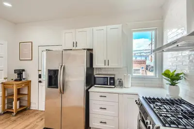 a kitchen with white cabinets and a stainless steel refrigerator at Remodeled 3 Bedroom Close to St Broadway And Sante Fe And CBD in Denver