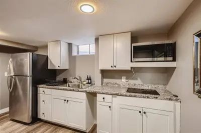 a kitchen with white cabinets and a stainless steel refrigerator at Basement Guest Suite With A Pool Table A Hot Tub And A TV in Denver