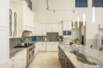a large kitchen with white cabinets and marble counter tops at Ultra Luxury Loft With A Fireplace In The Rooftop In RiNo in Denver