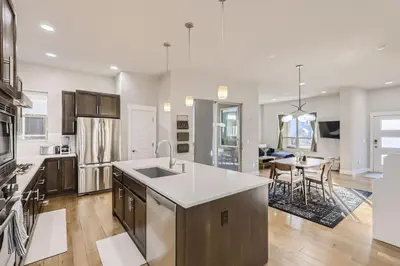 a kitchen with a kitchen island and a dining room at New Central Park Home Near DIA And 20mins to Downtown in Denver