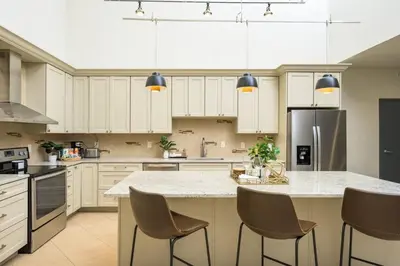 a kitchen with white cabinets and a large island with chairs at RiNo Loft With Parking And Mountain Views in Denver