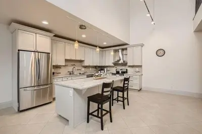 a kitchen with white cabinets and a large island with chairs at Luxury Loft With Skyline Viwes In RiNo in Denver