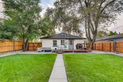 a backyard with a white house and a fence at Pet Friendly In West Denver Bungalow Near Meow Wolf in Denver