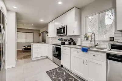 a kitchen with white cabinets and a large window at Pet Friendly In West Denver Bungalow Near Meow Wolf in Denver