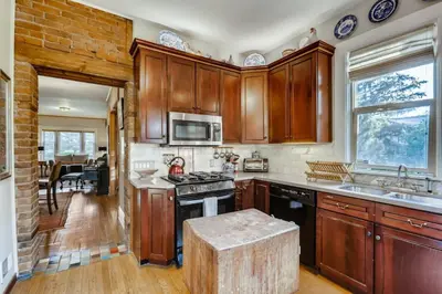a kitchen with wooden cabinets and a stove top oven at Artsy Victorian Great Location And Amazing Outdoor Space in Denver