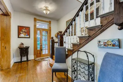 a living room with a staircase and a blue chair at Artsy Victorian Great Location And Amazing Outdoor Space in Denver