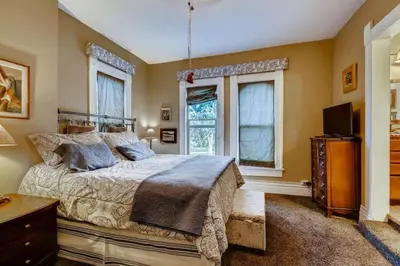 a bedroom with a bed and a tv and windows at Artsy Victorian Great Location And Amazing Outdoor Space in Denver