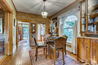 a dining room with a table and chairs and a brick wall at Artsy Victorian Great Location And Amazing Outdoor Space in Denver