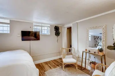 a bedroom with a bed and a chair and a mirror at Guest Suite With Kitchenette And A 5 star Location in Denver