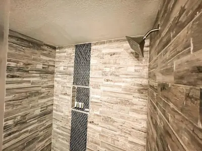a bathroom with a shower with a stone wall at Cozy Mountain Suite - hot tub, pool, gym - mins to lift in Keystone