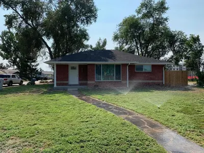 a house with a sprinkler in the yard at Island in the City - AWESOME 3 BR 2 BA 15 Min from DIA DT Anschutz in Commerce City