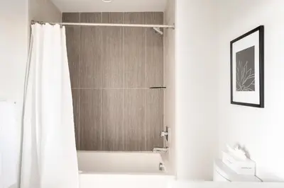 a bathroom with a shower with a white shower curtain at 2880 U505 Skytop Perspective at Espadin in Denver