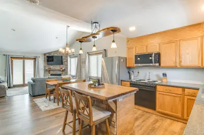 a kitchen with wooden cabinets and a table and chairs at Family-Friendly Retreat with Balcony in Fraser! in Fraser