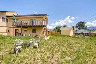 a yard with two chairs and a table in front of a house at Hike, Ski and Explore Townhome with Yard in Fraser! in Fraser