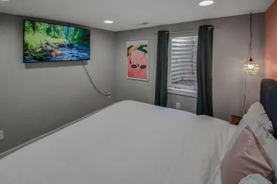 a bedroom with a white bed and a flat screen tv at 3 bed home with huge yard near Hidden Lake in Denver