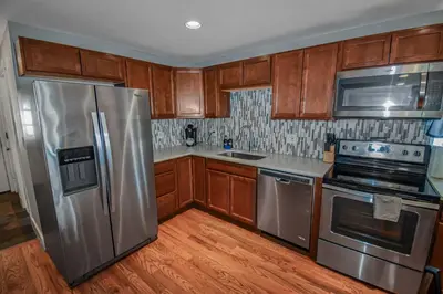 a kitchen with wooden cabinets and stainless steel appliances at 3 bed home with huge yard near Hidden Lake in Denver