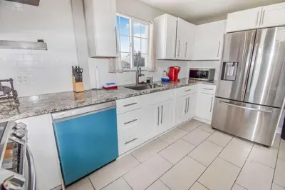 a kitchen with white cabinets and a stainless steel refrigerator at Charming Cowboy Bunkhouse in Denver in Denver