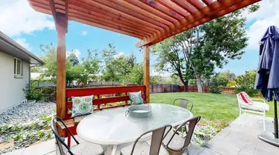 a table and chairs on a patio with a pergola at Charming four bedroom home with large yard and plenty of room for family in Centennial