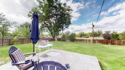 a patio with two chairs and an umbrella at Charming four bedroom home with large yard and plenty of room for family in Centennial