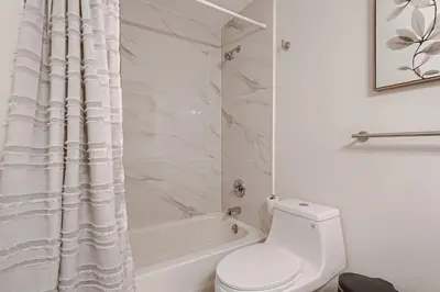 a white bathroom with a toilet and a shower curtain at The Arvada Retreat with HotTub, Games, Gym and Lounge in Arvada