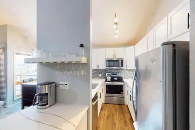 a kitchen with white cabinets and a stainless steel refrigerator at Flying Dutchman - Snow Owl Condo in Keystone