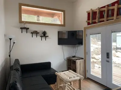 a living room with a couch and a flat screen tv at Native Spirit Cabin at Base Camp in Dumont