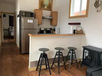 a kitchen with a counter and four bar stools at Native Spirit Cabin at Base Camp in Dumont