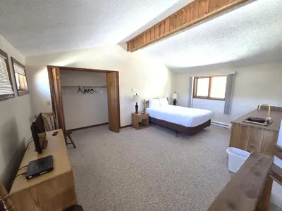a bedroom with a bed and a desk with a television at Timber Run in Winter Park