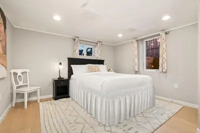 a white bedroom with a bed and a chair at CSU Hideaway with King Bed, Backyard Oasis in Fort Collins