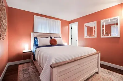 a bedroom with a large bed with orange walls at BRAND NEW Classic Fire Pit 2 Kings Pet Friendly in Arvada