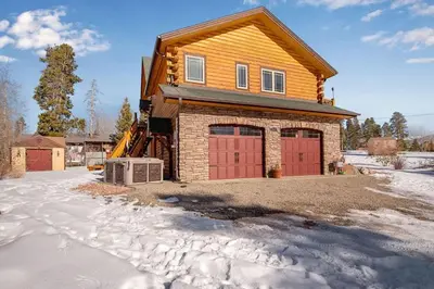 a house with red garage doors in the snow at Granby Modern Cabin - Hot Tub & Mountain Views in Granby
