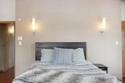 a bedroom with a bed with a gray blanket and pillows at Luxe & Leisure in Fairways- An Oasis in the Woods in Granby
