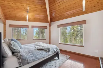a bedroom with a bed and two windows at Luxe & Leisure in Fairways- An Oasis in the Woods in Granby