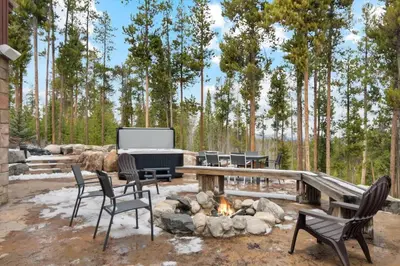 a patio with a fireplace and chairs and a tv at Luxe & Leisure in Fairways- An Oasis in the Woods in Granby
