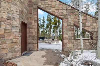 a brick building with an open door in a yard at Luxe & Leisure in Fairways- An Oasis in the Woods in Granby