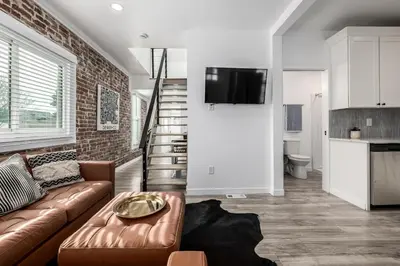 a living room with a brown couch and a brick wall at Great Remodeled Denver Bungalow in Denver