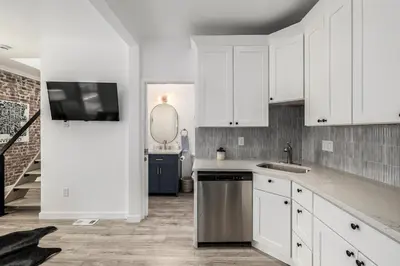 a kitchen with white cabinets and a sink and a tv at Great Remodeled Denver Bungalow in Denver