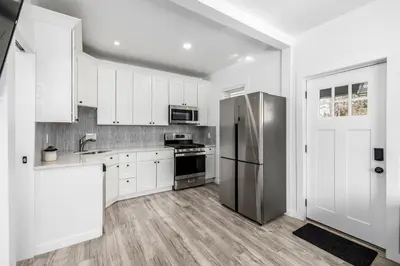 a kitchen with white cabinets and a stainless steel refrigerator at Great Remodeled Denver Bungalow in Denver