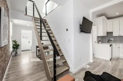 a staircase in a living room with white walls and wooden floors at Great Remodeled Denver Bungalow in Denver