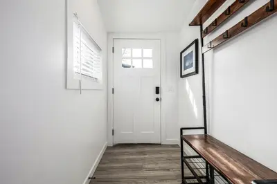 a hallway with a white door and a wooden bench at Great Remodeled Denver Bungalow in Denver