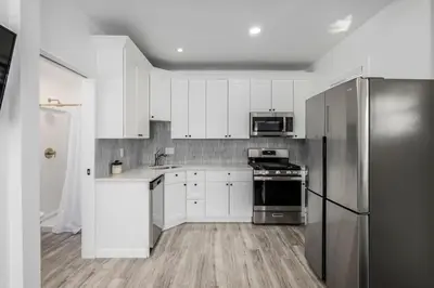 a kitchen with white cabinets and a stainless steel refrigerator at Great Remodeled Denver Bungalow in Denver