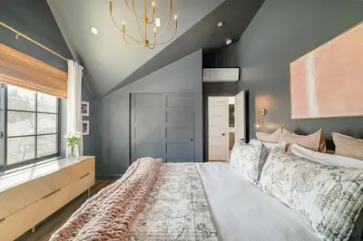 a bedroom with a large bed and a chandelier at Luxe Designer Flat on Sloans Lake with Rooftop Deck in Denver