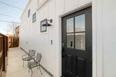 a black door on a white building with two chairs at Luxe Designer Flat on Sloans Lake with Rooftop Deck in Denver