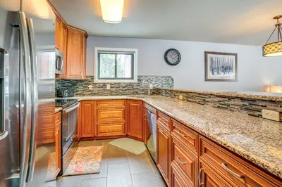 a kitchen with wooden cabinets and a stainless steel refrigerator at Home with Mtn Views in Frisco Near 3 Ski Resorts! in Frisco