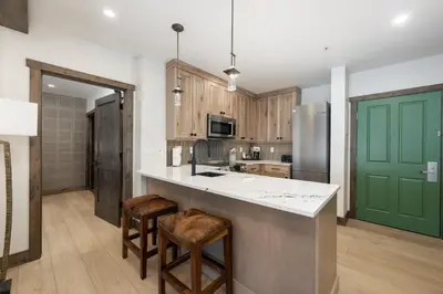 a kitchen with wooden cabinets and a green door at Select Unit 2509 - Zephyr Mountain Lodge condo in Winter Park