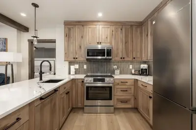 a kitchen with wooden cabinets and a stainless steel refrigerator at Select Unit 2509 - Zephyr Mountain Lodge condo in Winter Park