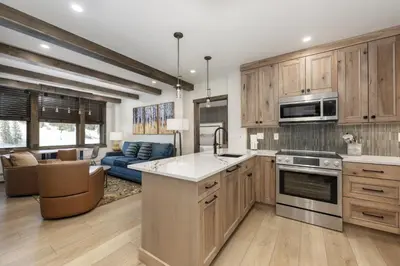 a kitchen with wooden cabinets and a living room at Select Unit 2509 - Zephyr Mountain Lodge condo in Winter Park